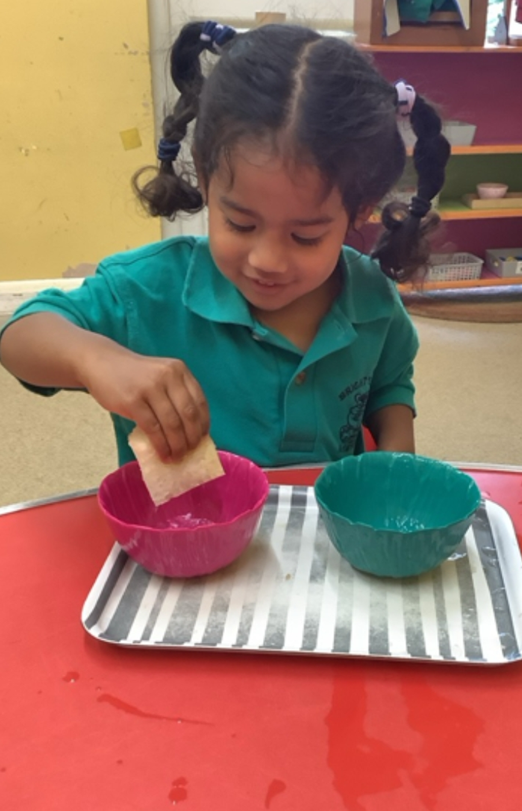 A child practising a Montessori pouring activity with two bowls on a tray